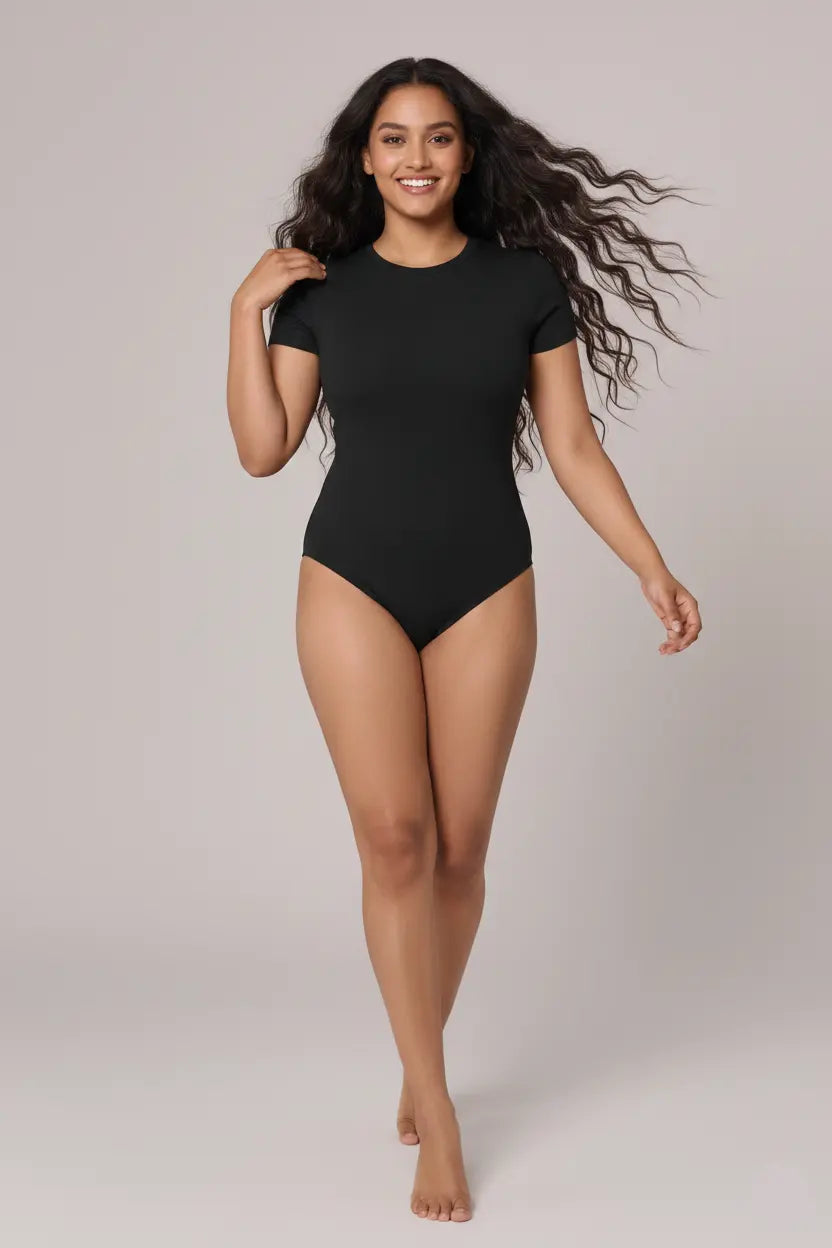Woman wearing a black bodysuit on a plain background