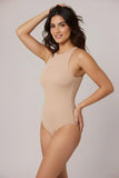Woman wearing a beige bodysuit against a plain background