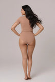 Woman wearing a beige bodysuit against a plain background