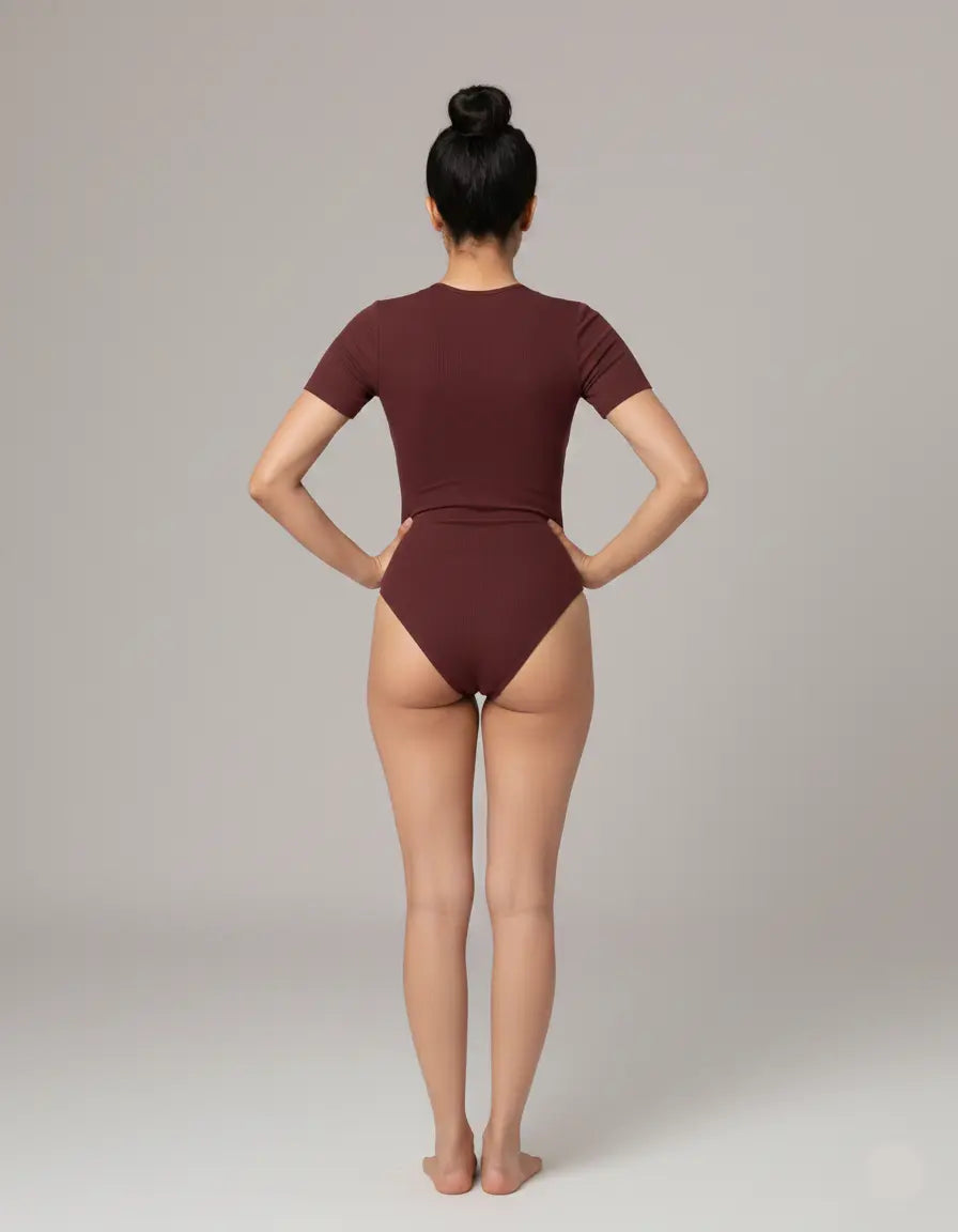 Person wearing a burgundy swimsuit on a plain background