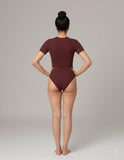 Person wearing a burgundy swimsuit on a plain background