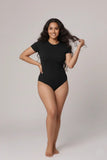 Woman wearing a black bodysuit against a plain background