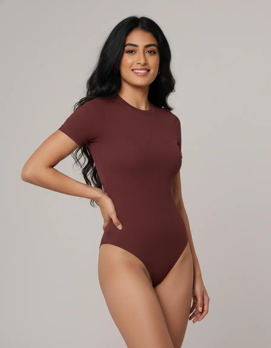Woman wearing a maroon bodysuit against a plain background