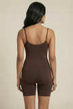 Woman wearing a brown bodysuit against a beige background