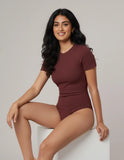 Woman wearing a maroon swimsuit against a plain background