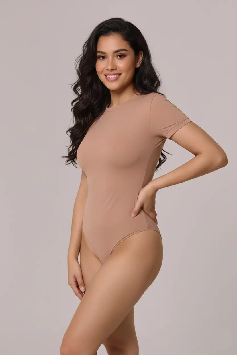 Woman wearing a beige bodysuit against a plain background